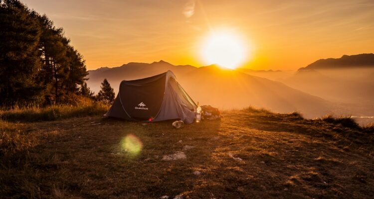 dome tent on mountain top with sun as background photo